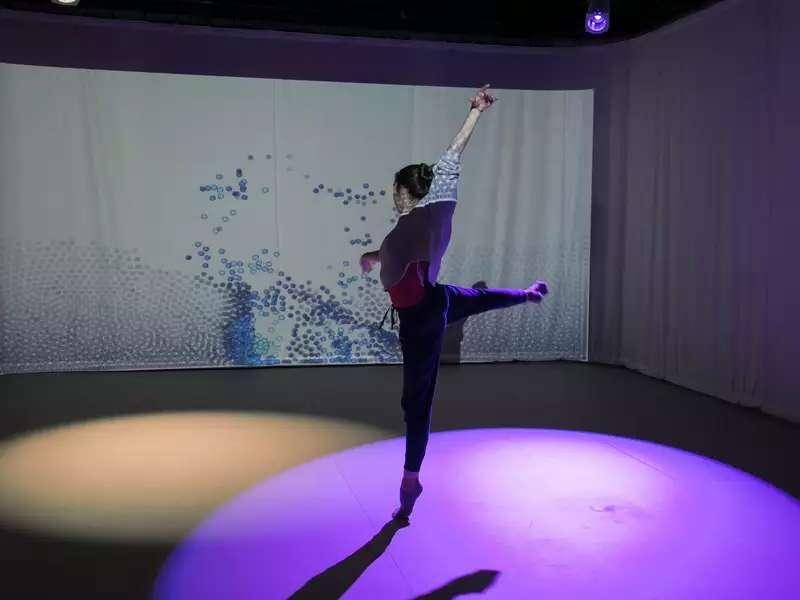 Female student dancing in a purple spotlight